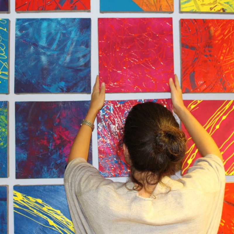 Ragazza che appende un quadro colorato